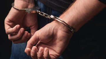 Close up of male hands in bracelets behind back